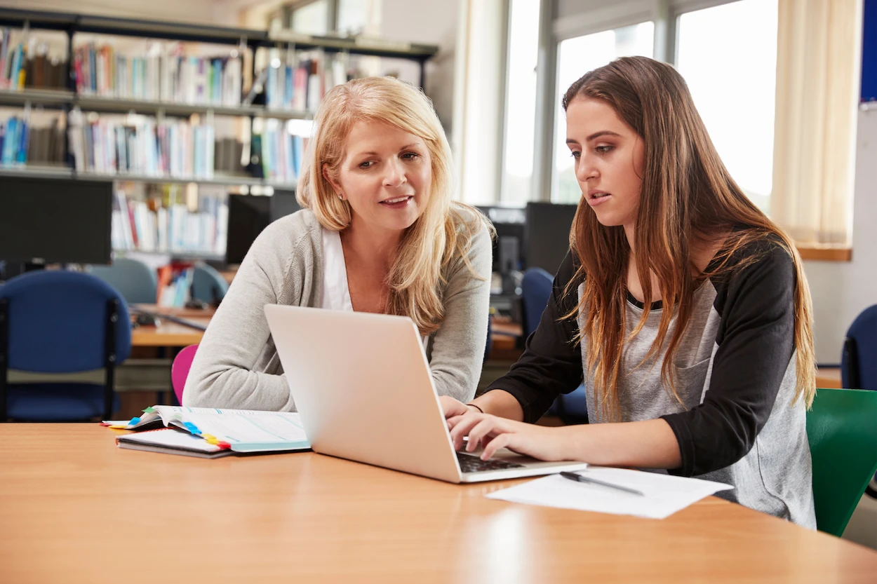 University tutor and student working together on laptop